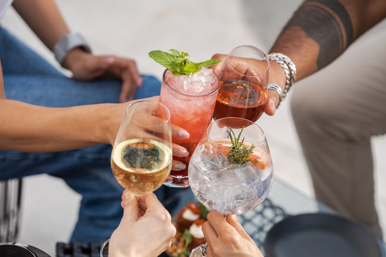 gallery-1 A joyful toast among friends with diverse cocktails, capturing a moment of celebration and camaraderie outdoors.