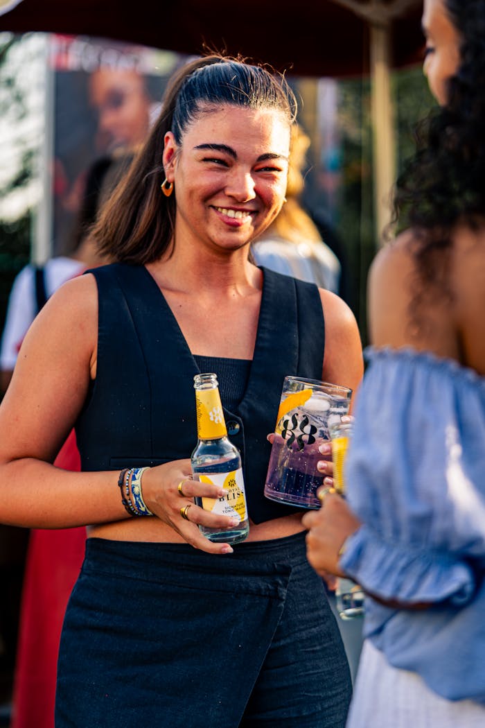 why-choose-us Smiling woman holding drinks at an outdoor summer festival, enjoying time with friends.