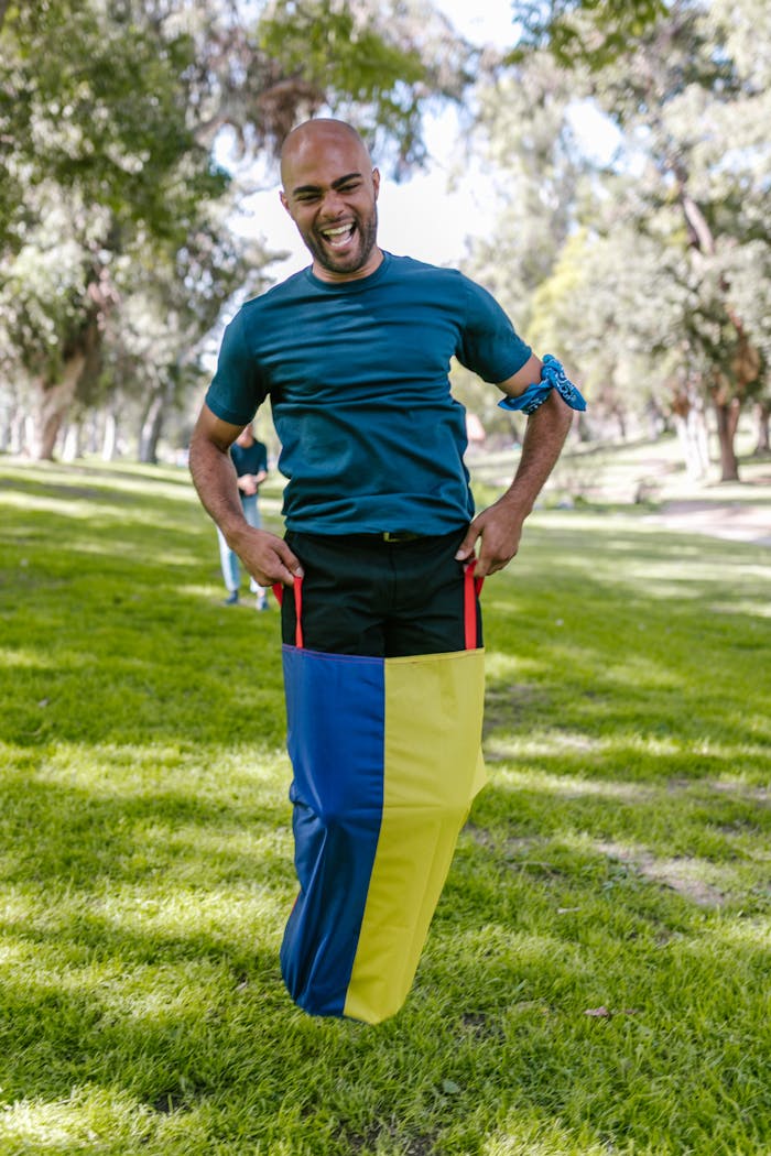 gallery-3 Smiling man participates in a vibrant sack race outdoors, showcasing team spirit.